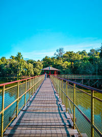 Footbridge on footpath against clear blue sky