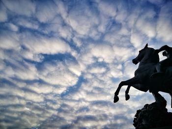 Low angle view of silhouette statue against sky