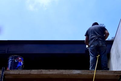 Rear view of man standing against blue sky