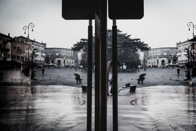 People on wet street amidst buildings in city