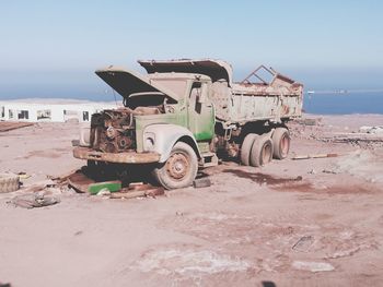 Abandoned truck t beach against sky during sunny day