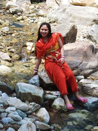 Portrait of smiling young woman sitting on rock