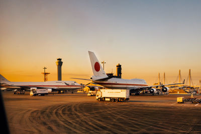 Airplane on airport runway against sky during sunset