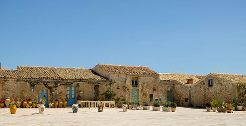 People in front of historic building against clear blue sky