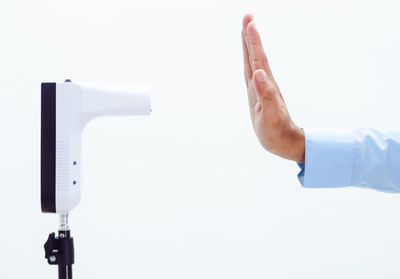 Close-up of hand holding paper over white background