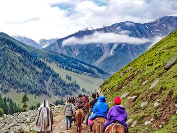 Rear view of people riding horses on mountain