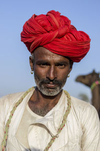 Close-up portrait of man wearing red turban against clear sky