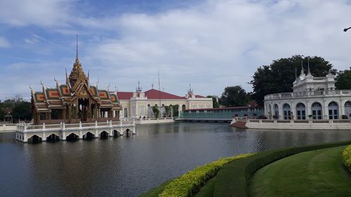 View of building by river against cloudy sky