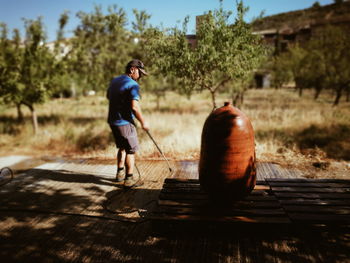 Rear view of man working on wooden floor during sunny day