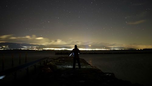 Rear view of silhouette man standing against sky at night