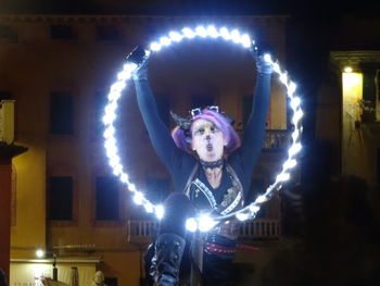 Portrait of man with illuminated ferris wheel at night