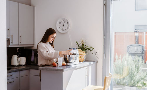 Young woman standing by table at home