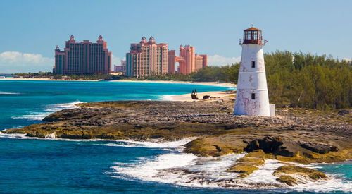 Lighthouse by sea against sky