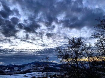 Silhouette bare trees on snowcapped landscape against sky