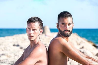 Portrait of young male friends at beach on sunny day