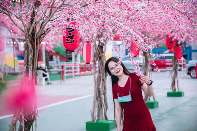 Portrait of woman standing by pink cherry blossom