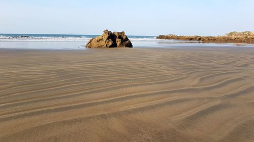 Rock formation on beach against sky