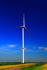 Low angle view of windmill on field against blue sky