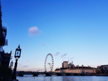 View of ferris wheel in city against blue sky