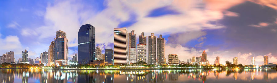 Panoramic view of modern buildings by city against sky