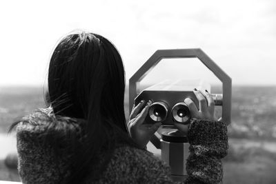 Rear view of woman holding coin-operated binoculars