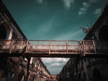Low angle view of old footbridge against sky