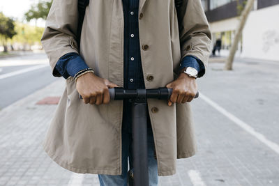 Man riding on e-scooter, partial view