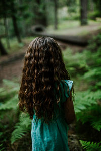 Young girl looking away at forest trail