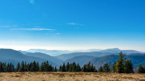 Scenic view of landscape and mountains against blue sky