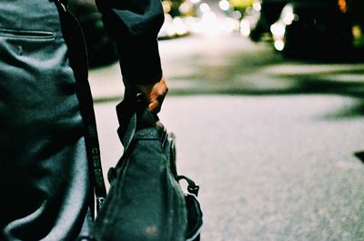 Mid section of man carrying bag on street