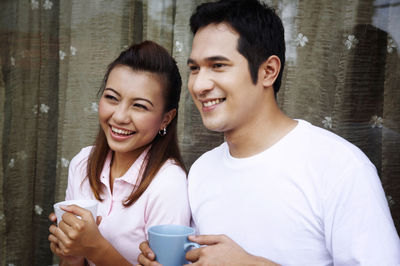 Couple talking while having coffee against wall