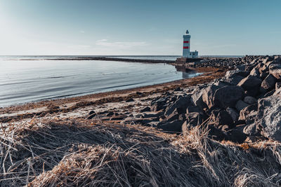 Lighthouse by sea against sky