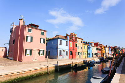 Boats in canal amidst buildings against sky