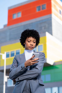 A cool young curly haired african american lady dressed professionally talking on her phone outdoors