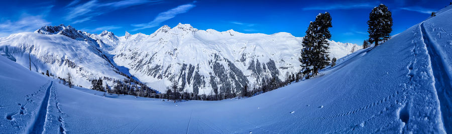 Panoramic view of snowcapped mountains against blue sky