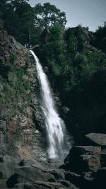 Scenic view of waterfall in forest against sky