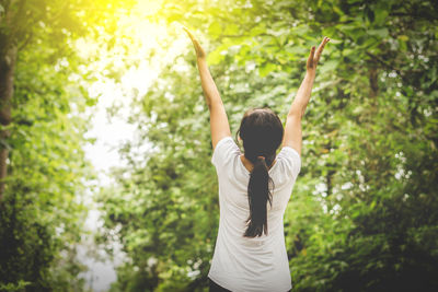 Rear view of woman exercising against trees