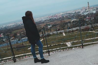 Rear view of woman standing on railing against cityscape