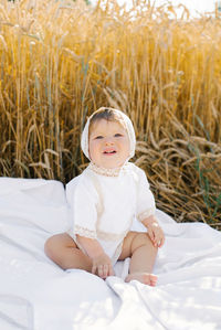 Child boy in white clothes is relaxing in the fresh air in a field