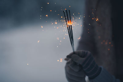 Low section of man holding sparkler at night