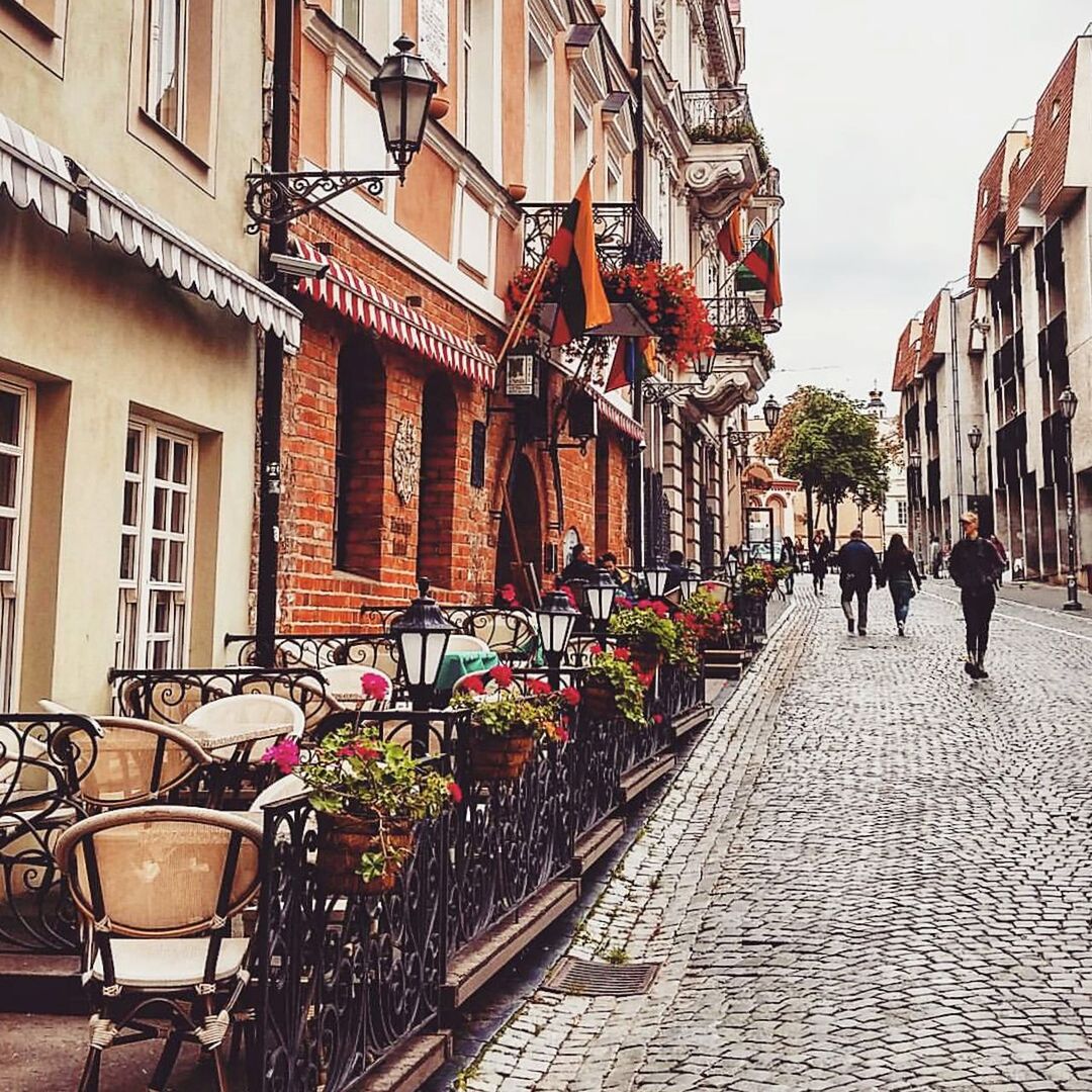 building exterior, architecture, built structure, cobblestone, city, street, residential building, residential structure, person, men, city life, building, potted plant, house, incidental people, the way forward, outdoors, day, walking