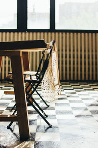 Empty chairs and table against window of building