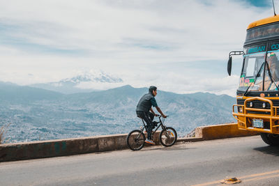 Man riding bicycle on mountain against sky