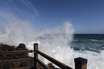 Waves splashing on shore against sky