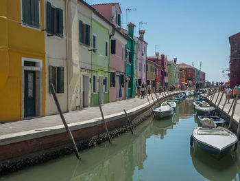 Boats moored on canal amidst buildings in city
