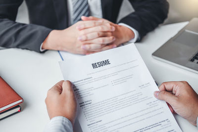 Midsection of man holding paper while sitting on table