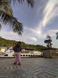 Man standing by palm trees against sky