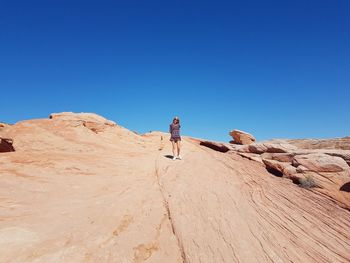 Man on rock against clear blue sky