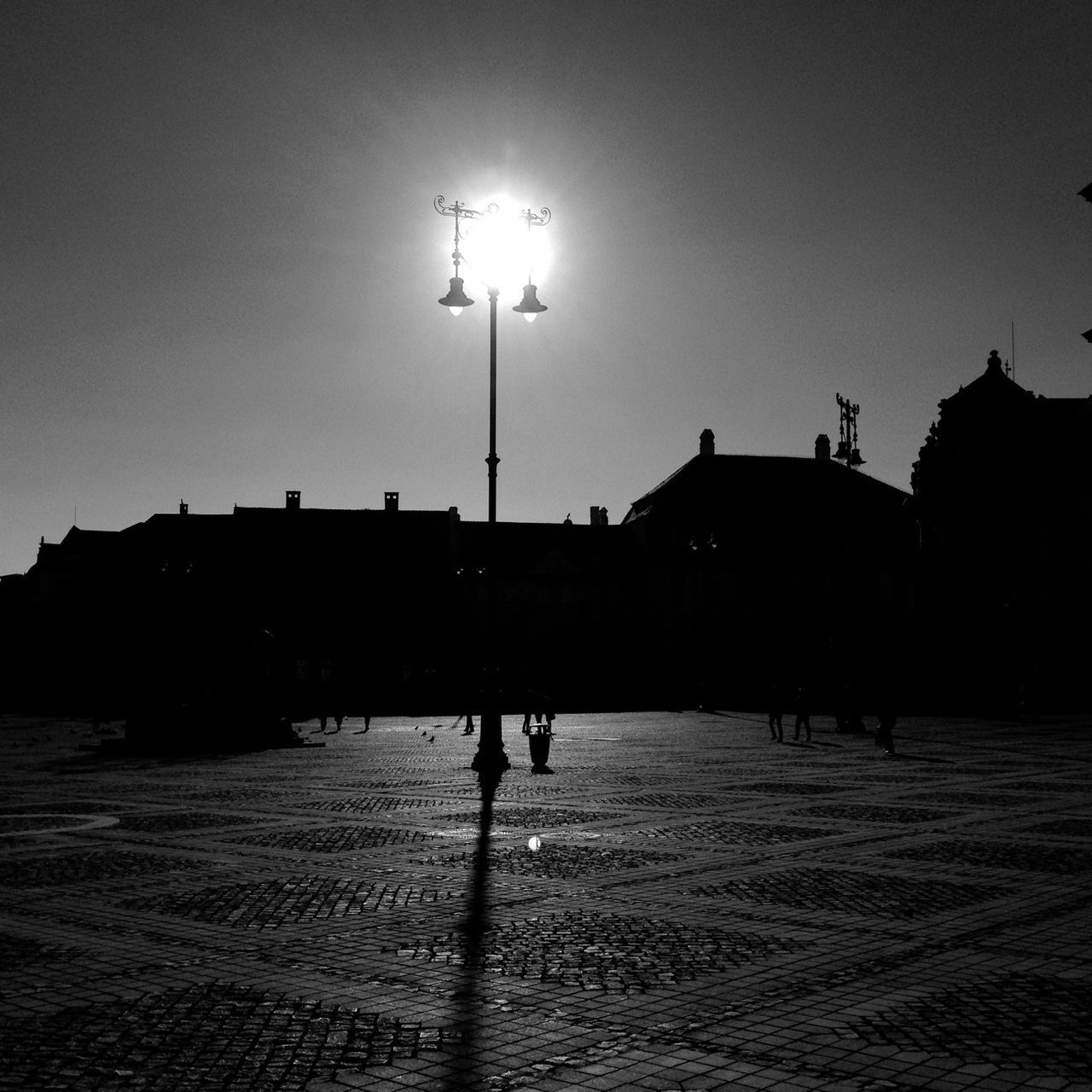 street light, building exterior, silhouette, architecture, built structure, lighting equipment, sky, clear sky, illuminated, street, city, sun, men, sunset, dusk, outdoors, night, sunlight, walking