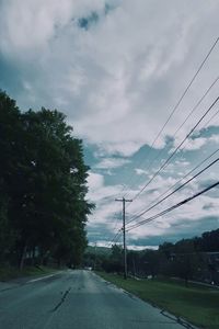 Road by trees against sky